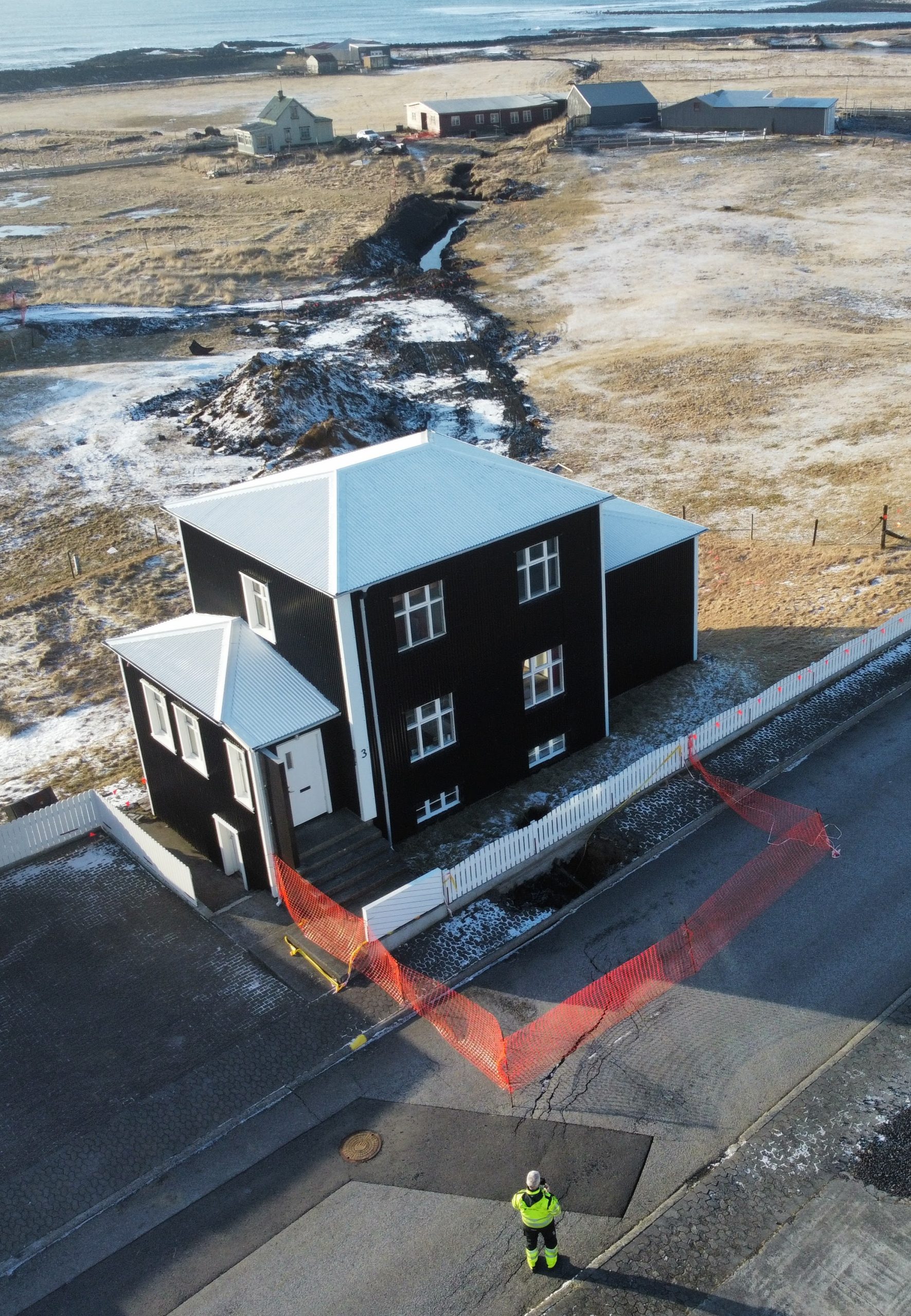 Myndin sýnir stóra sprungu sem liggur í gegnum bæinn og undir nokkur hús.