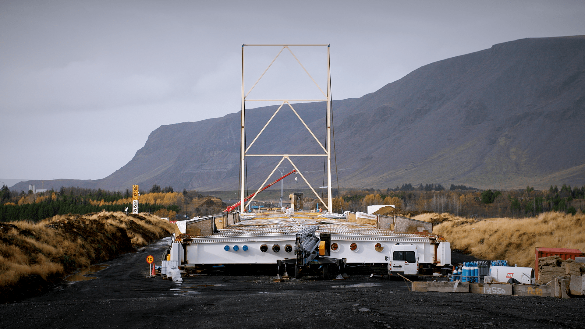 Brúargólfið hefur verið sett saman á landi og er nú undirbúið fyrir flutning yfir Ölfusá. Í bakgrunni sést mastur nýju brúarinnar.