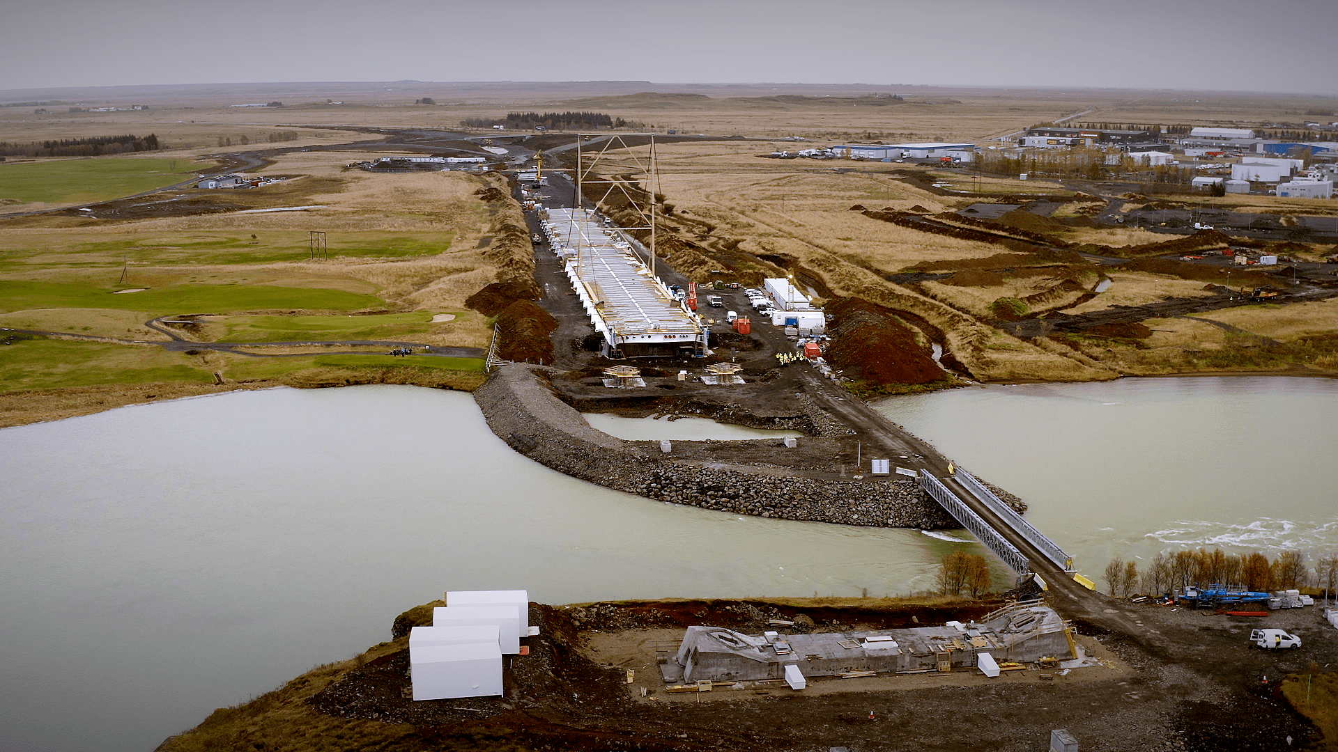 Horft yfir framkvæmdasvæðið við Ölfusá þar sem unnið er að smíði nýrrar brúar. Brúargólfið hefur verið sett saman á landi og undirbúningur stendur yfir fyrir drátt þess yfir ána.